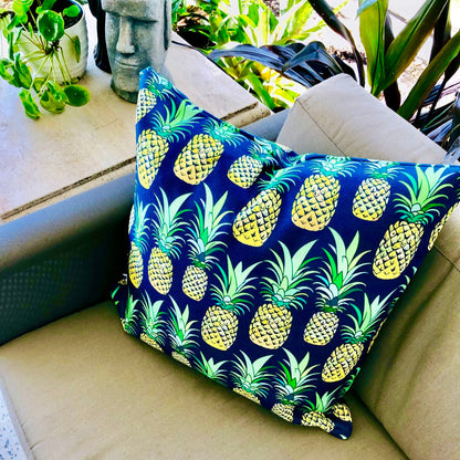 Throw pillow cover with a deep navy background featuring a colorful pineapple pattern in shades of green and yellow. Left Coast Supply