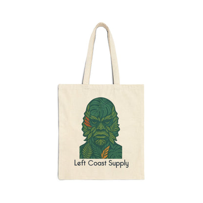 An off-white canvas tote bag with two handles, featuring a stylized green leaf-patterned character graphic and the text 'Left Coast Supply' printed on the front, set against a plain white background.