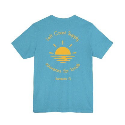 Blue t-shirt with yellow graphic of sunset with souvenirs for locals written. Left Coast Supply