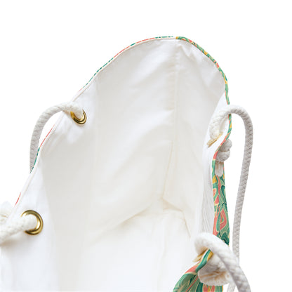 Beach tote with a watercolor pattern featuring mermaids and sunset hues, with white nautical rope handles. Left Coast Supply