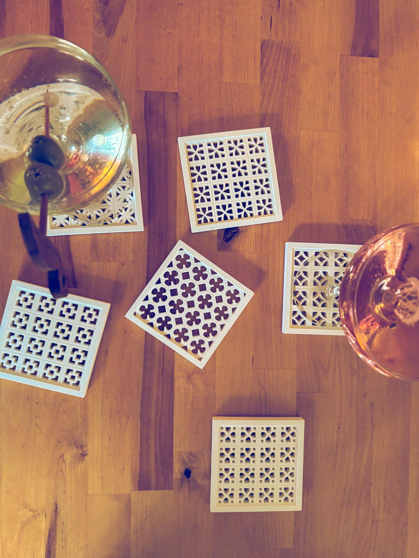 White breeze-block coasters with cocktail glasses on a wood table